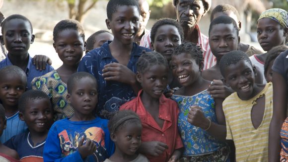A group of smiling children are standing next to each other.