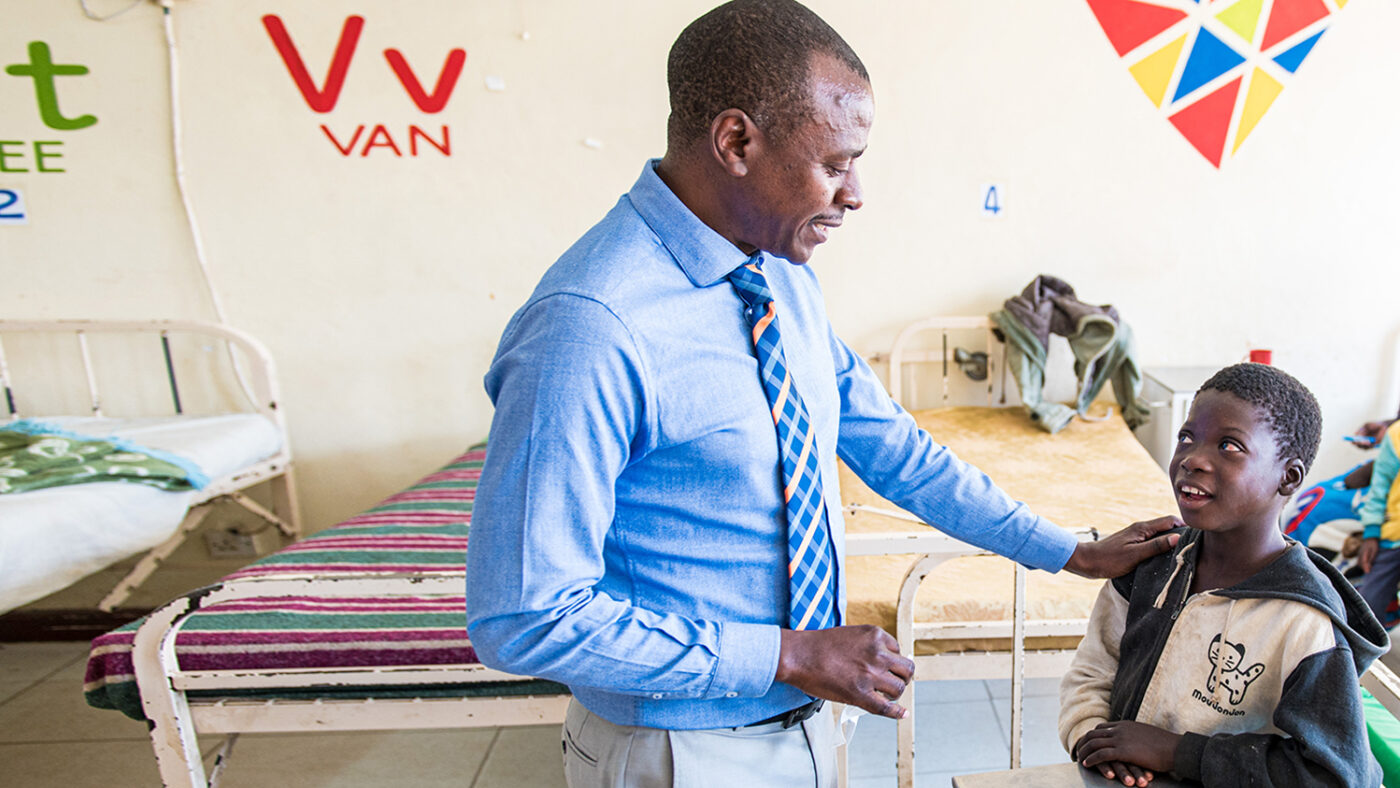 Dr Msukwa puts his hand on the shoulder of a young patient.