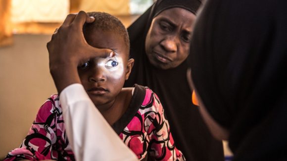 Asha's eyes are examined by a specialist, who shines a light into them to check for cataracts.