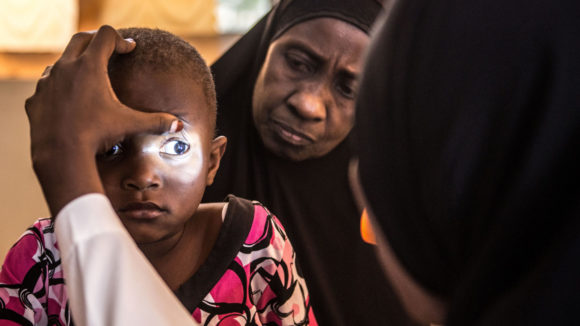 Asha's eyes are examined by a specialist, who shines a light into them to check for cataracts.