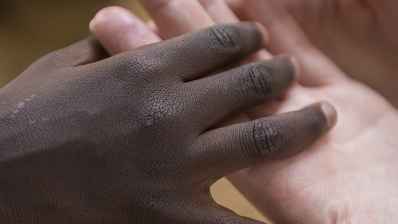 A close up photo of two people holding hands.