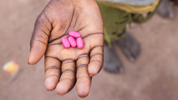 A child in Senegal holds antibiotic tablets in his hand.