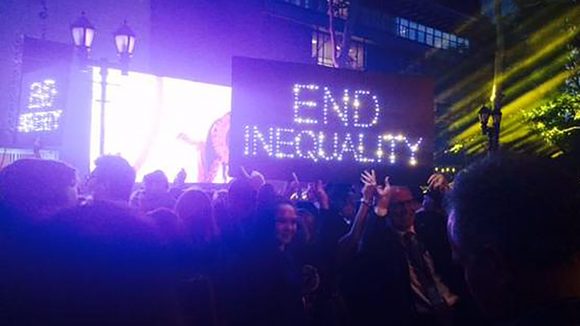 An illuminated sign that reads 'End inequality' is held up amid the darkness at the Light the Way event in London.