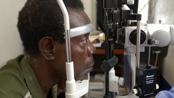 A man looks into a eye testing machine.