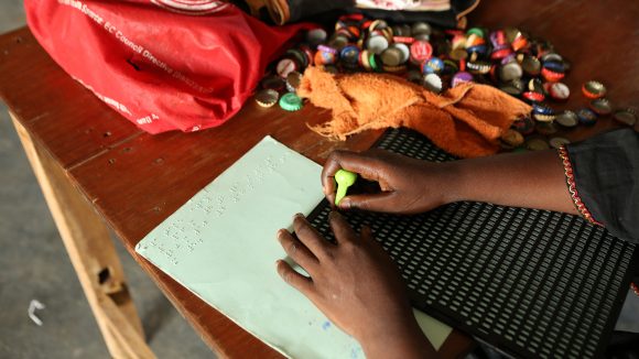 A photo of someone's hands on a piece of paper with braille on it.