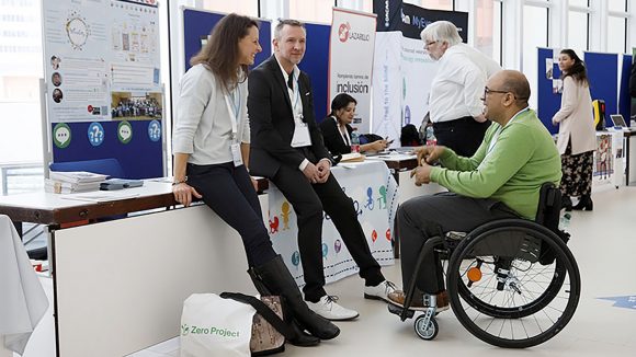 Attendees at the Zero Project conference chat next to one of the stands.