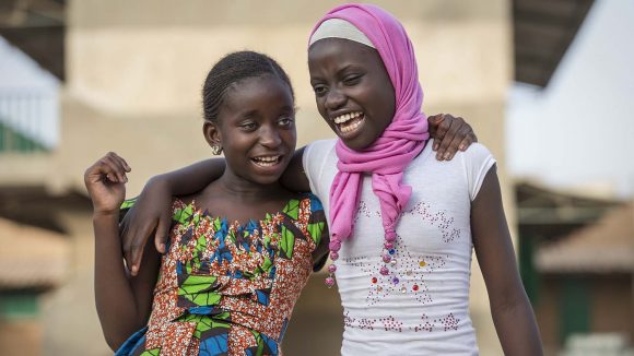 Two young girls with their arms around each other.