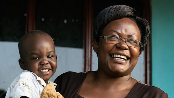 A laughing while holding a baby.