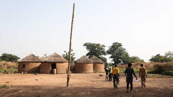 Three people walking in a village in Ghana.