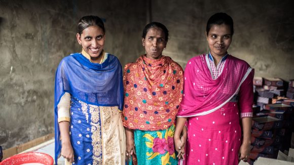 Three women standing side by side and smiling.