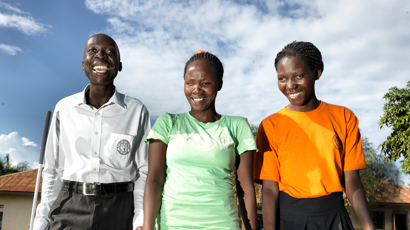 Three social inclusion participants are in a line smiling at the camera.