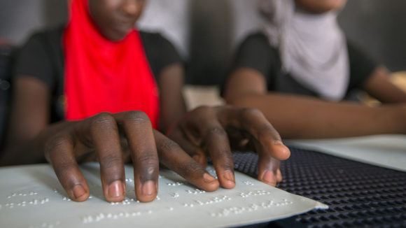 A student in Senegal reads braille in the classroom.
