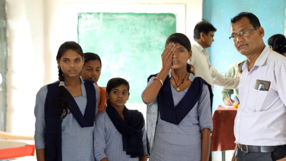A student covers one eye during an eye test at a school in India.
