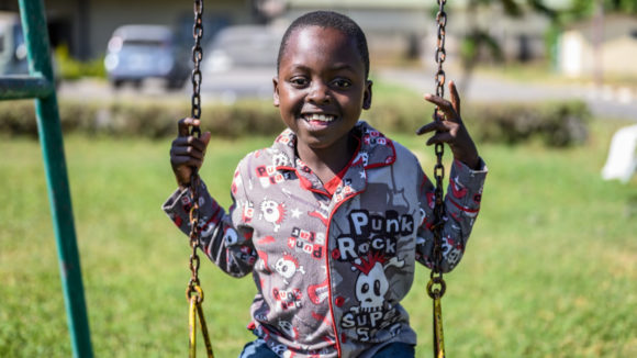 Lovemore on a swing smiling after his operation