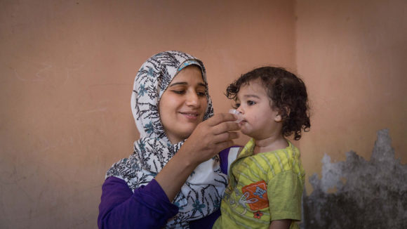 A mum gives a young child antibiotics to treat trachoma.