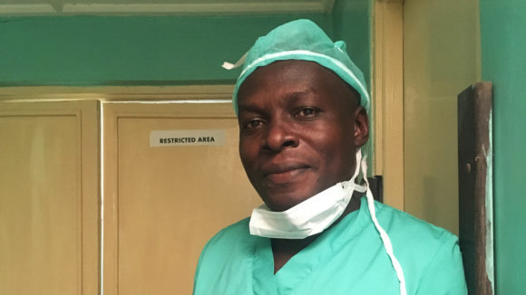 A man in scrubs smiles.