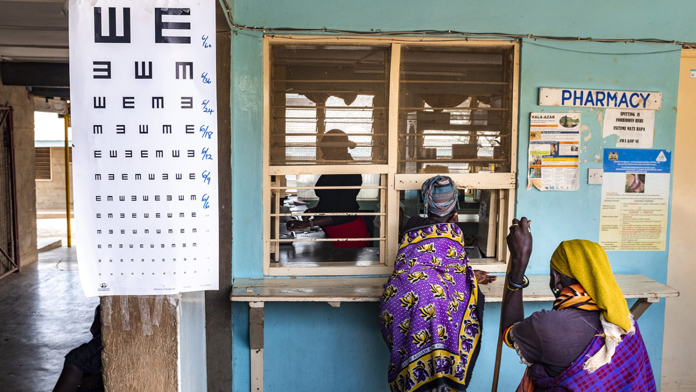 A women leans against a reception desk at a health clinic.