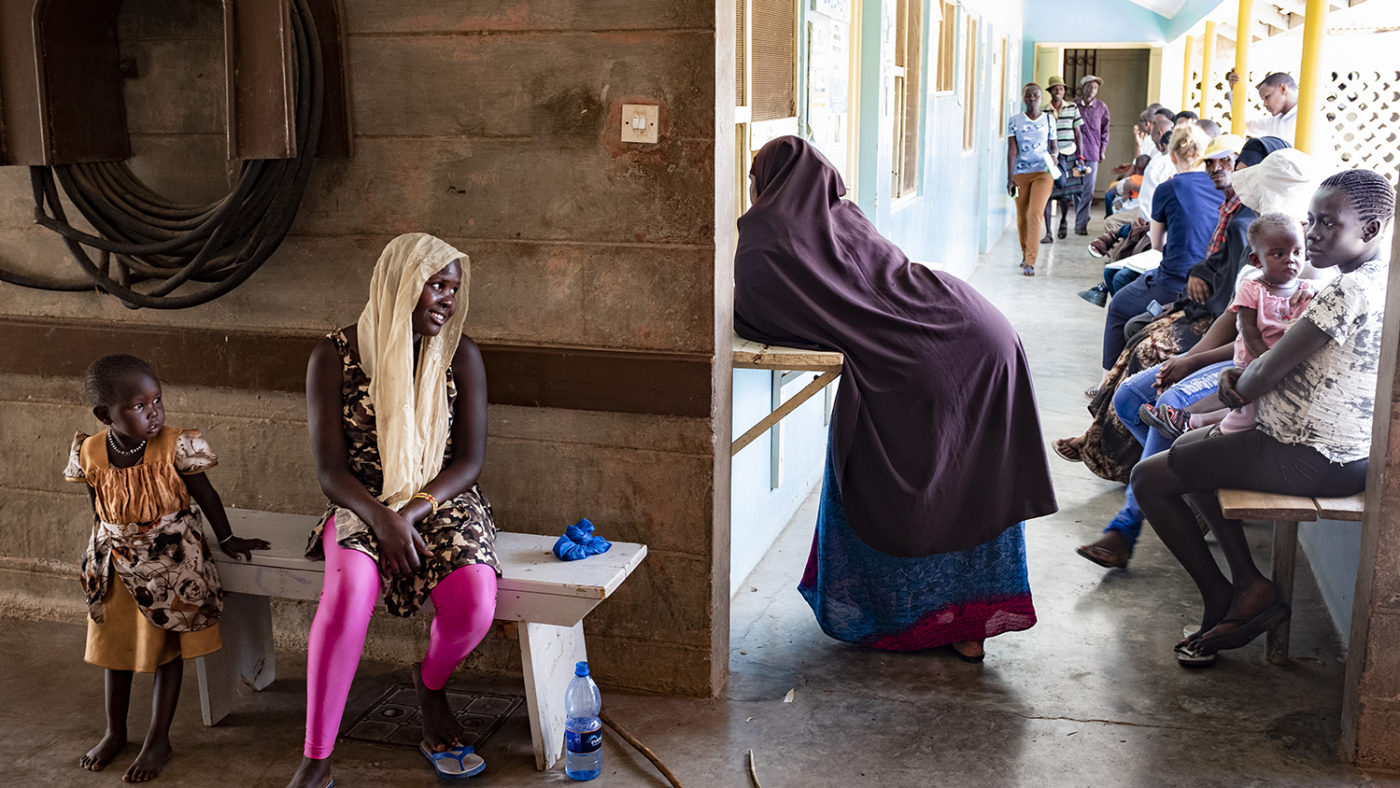 A women leans against a reception desk at a health clinic.