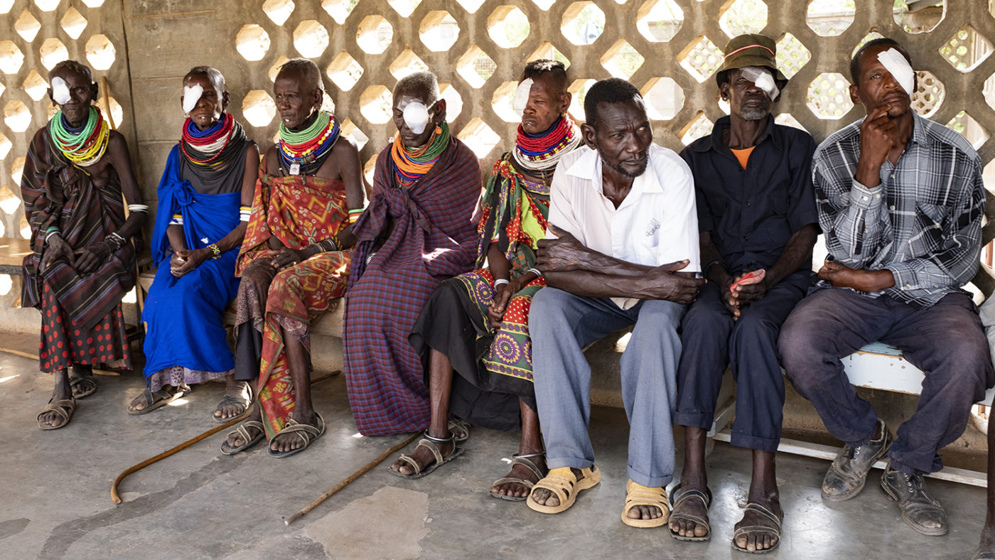People with patches over one eye sit at a health clinic.
