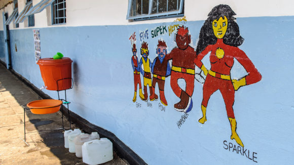 A mural on a school wall showing five superhero characters.