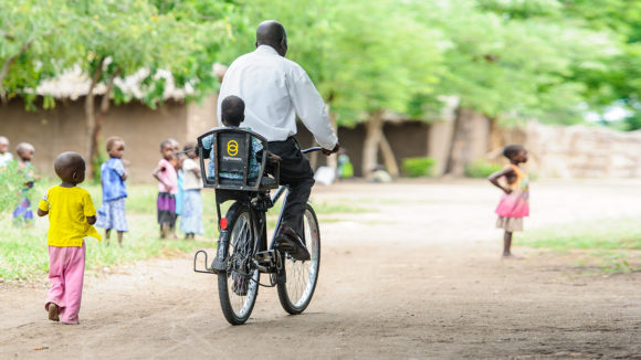 A man rides a bike with a child on the back.
