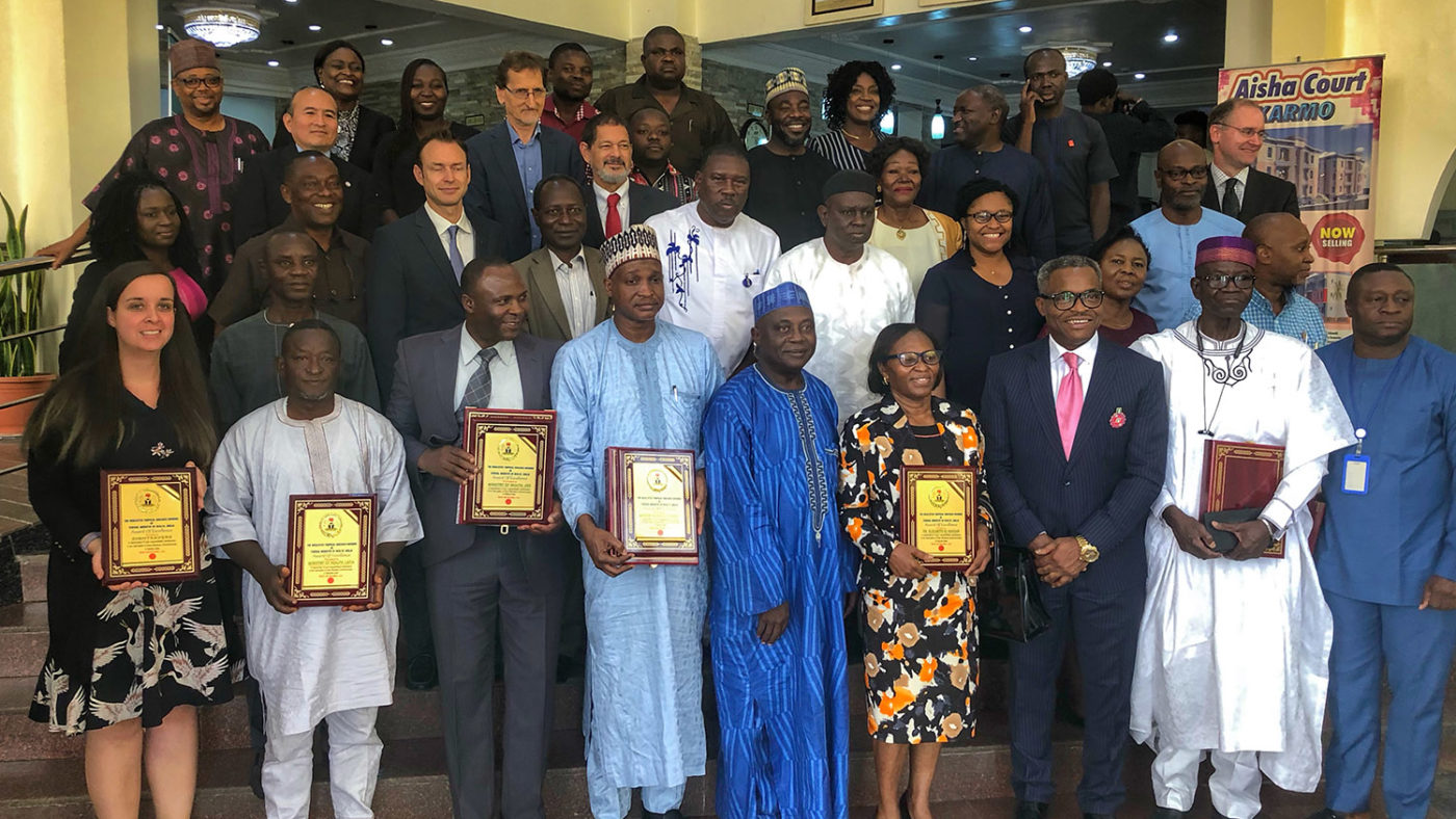 A large group of people stand with their awards for tackling river blindness in Nigeria.