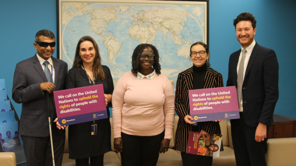 Sightsavers staff at the UN hold signs saying 'We call on the United Nations to uphold the rights of people with disabilities'.