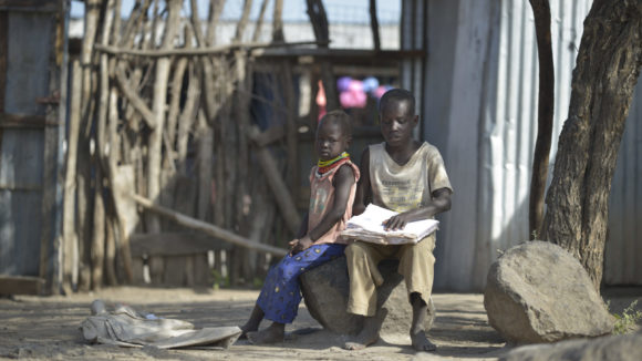James reads with his sister, sitting outside