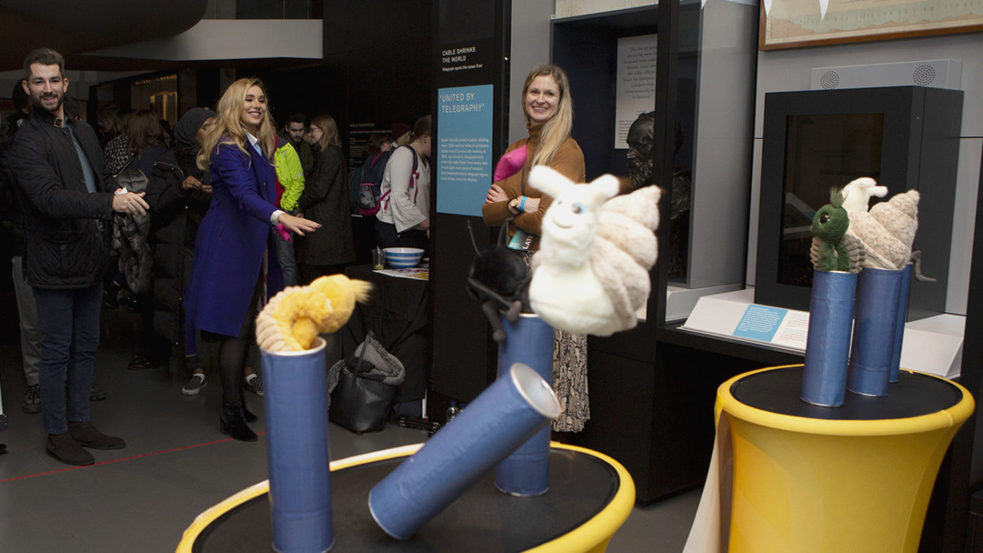Science Museum Lates attendees play a coconut-shy styled game where participants throw bean bags at plush toys.