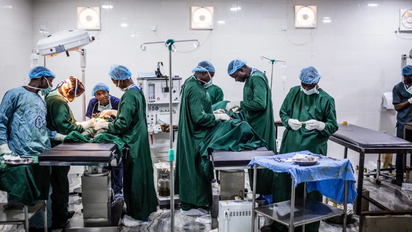Surgeons stand around an operating table.