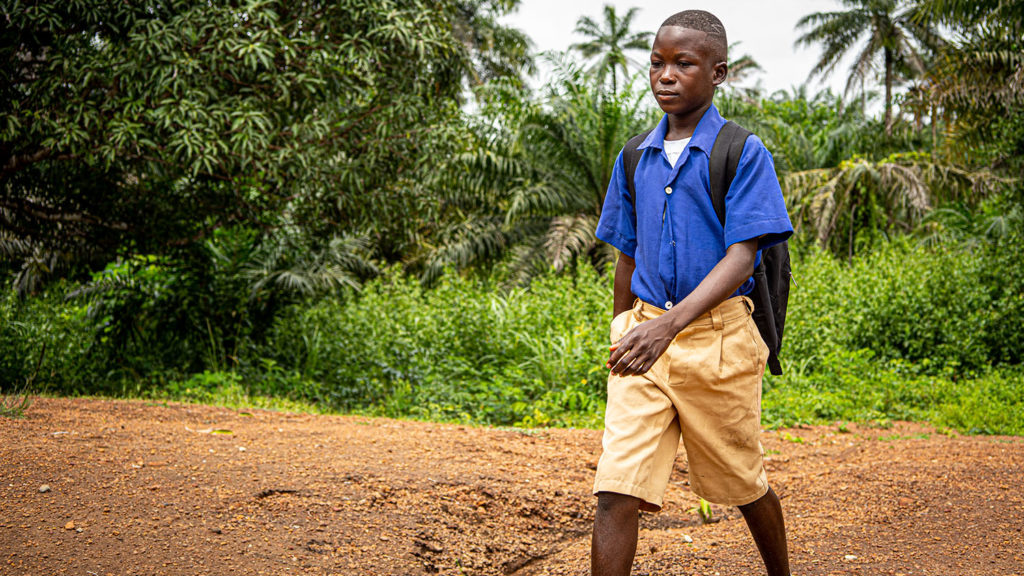 Abdul walks to school in his school uniform.