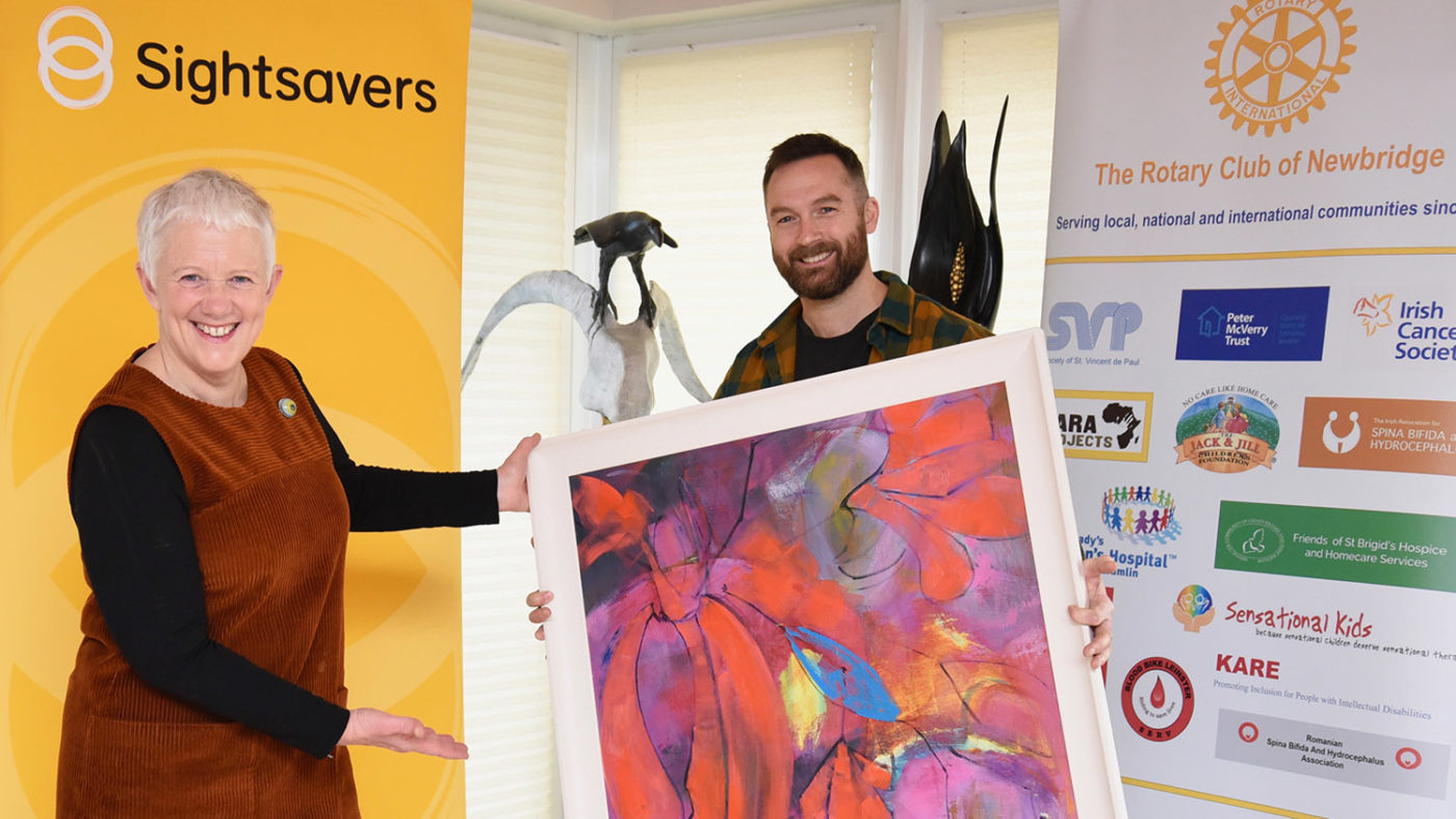 A man and woman pose with a piece of art.