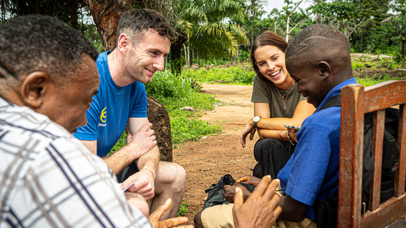 Abdul, Padraic and two other adults sitting, smiling and chatting.