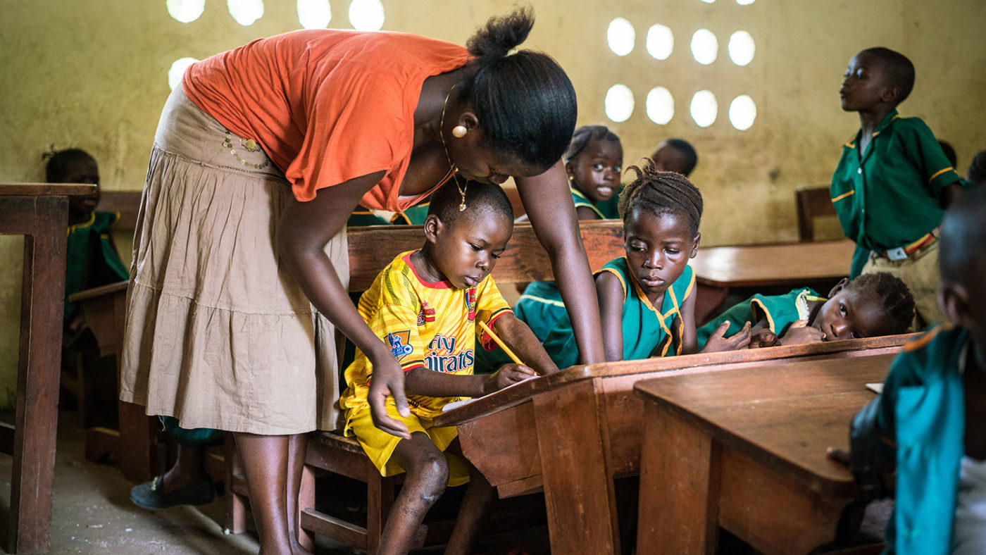 A teacher assists physically disabled student at school.