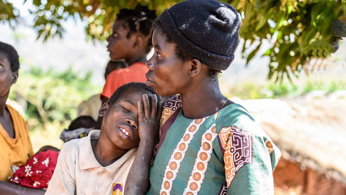 Eight-year-old Taonga leans into his mum, holding his hand to his eye.