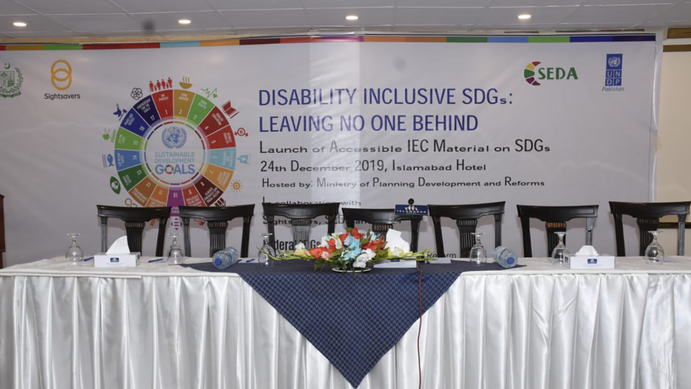 A table is laid out in front of a sign that says 'Disability Inclusive SDGs: Leaving no one behind'