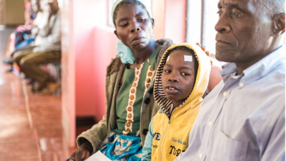 Zelina comforts her eight-year-old son, Taonga, as they wait in the queue at the hospital.