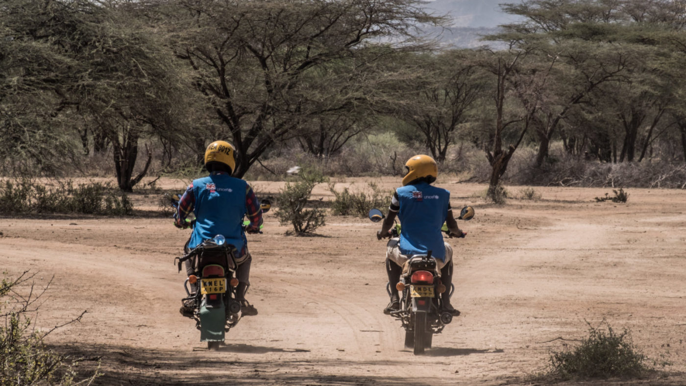 Two men riding motorcycles in rural Kenya.