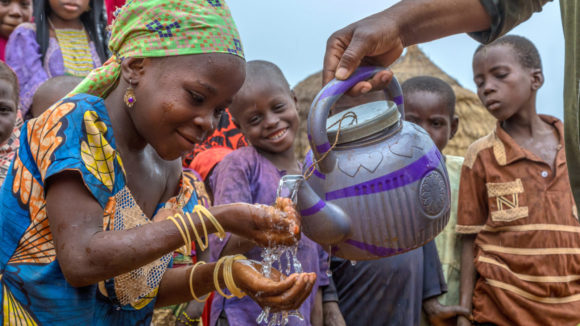 Children washing hands outside.