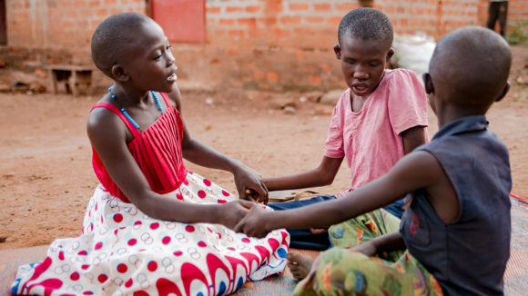 A girl with deafblindness plays with her siblings.