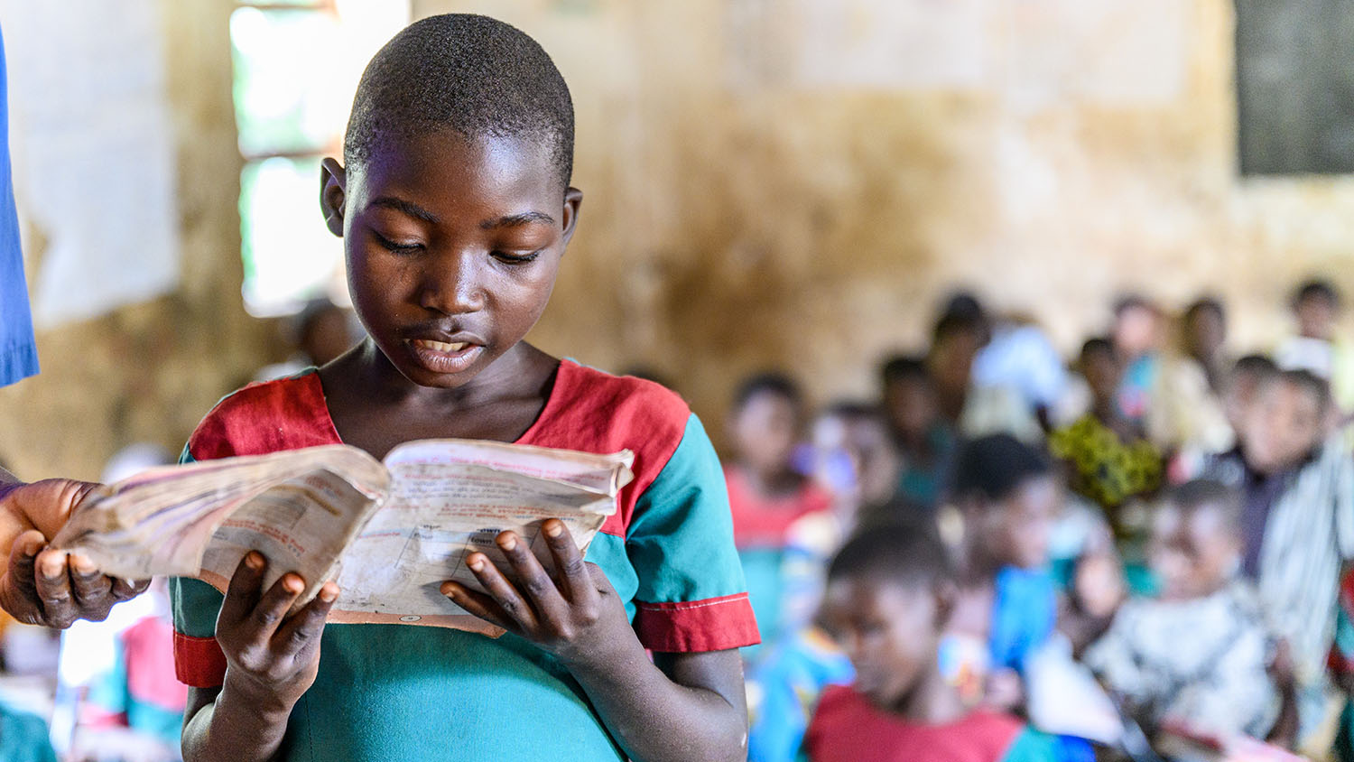 Mary stands up in class and reads from a book.