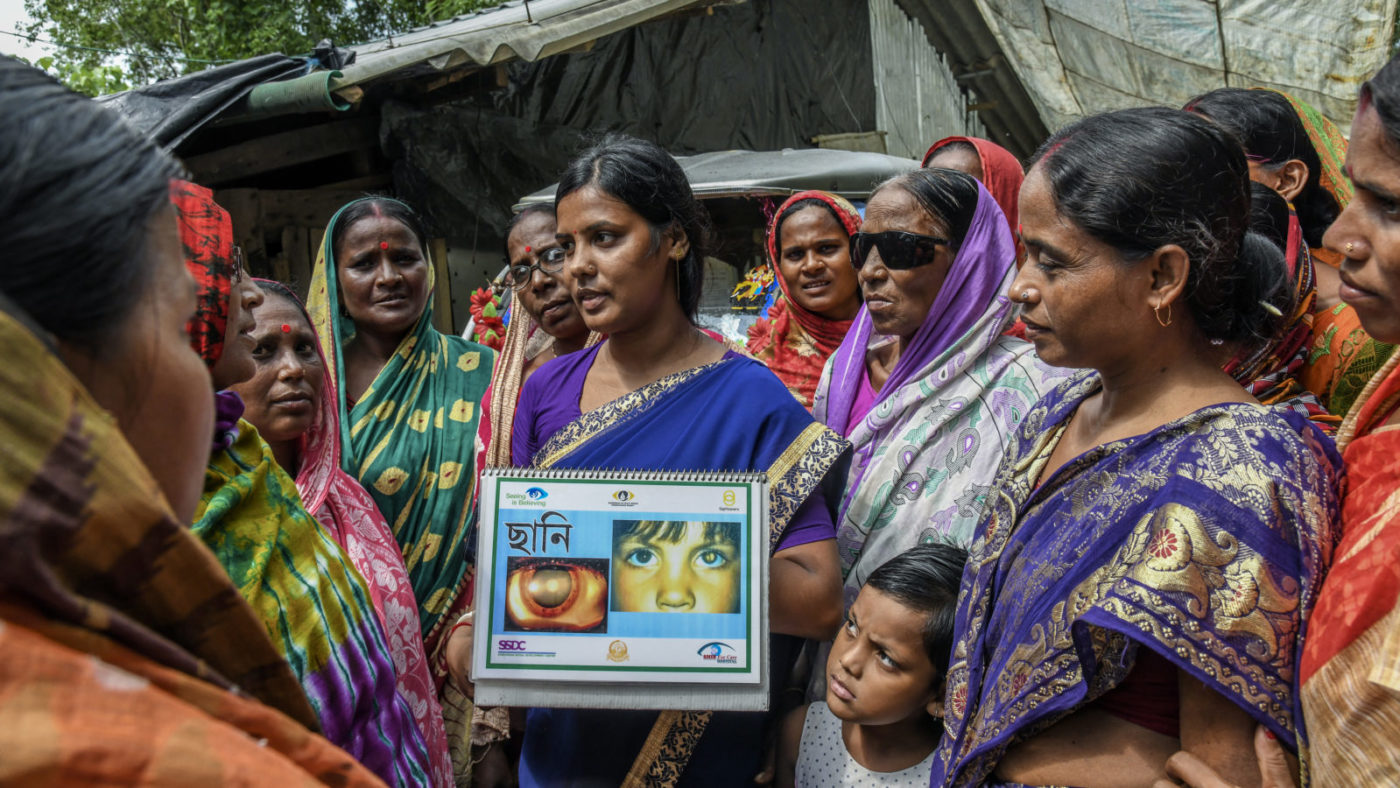 Women showing health information to a crowd.