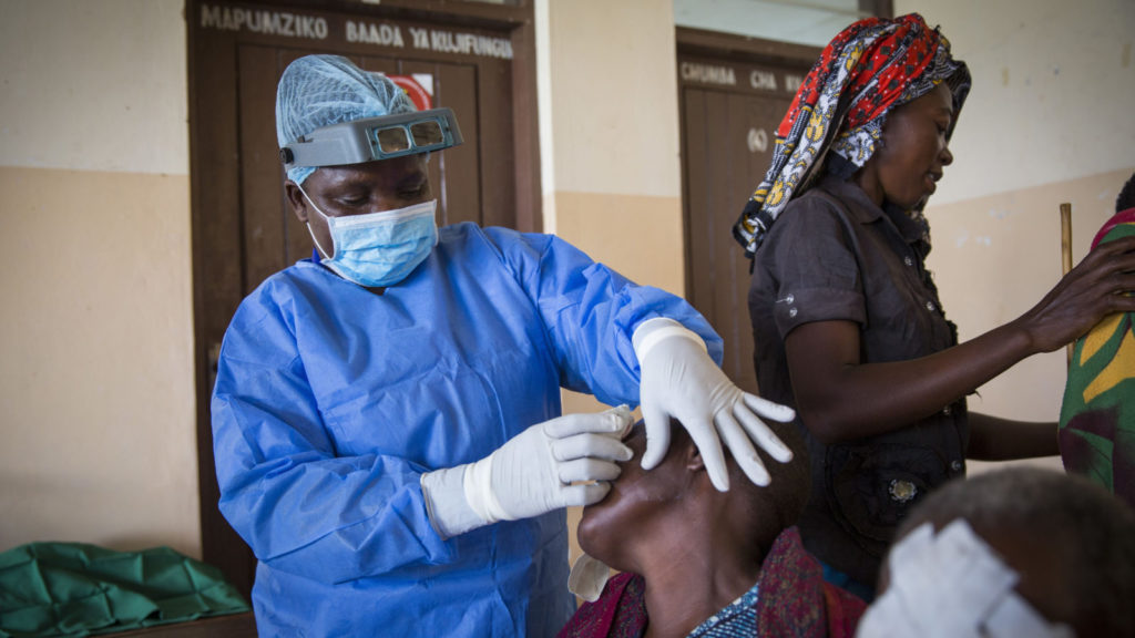 A surgeon taking a bandage off of a patients eye.