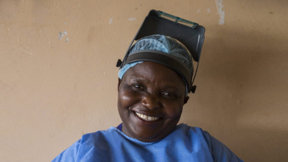 A woman smiling. She is dressed in surgical scrubs.