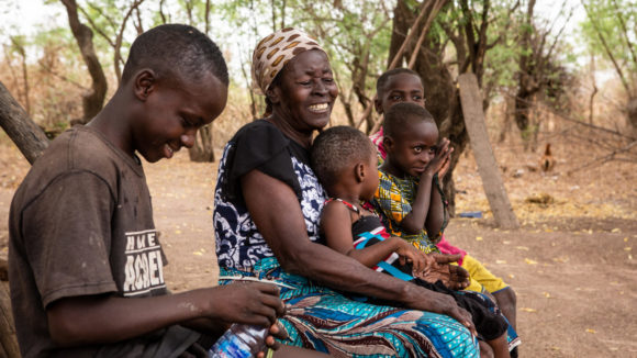 Women smiling, sat down with children.