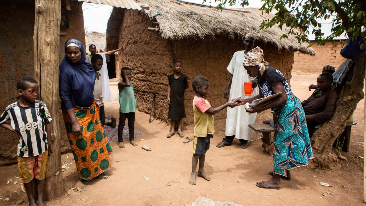 Women handing out medicine in a village.