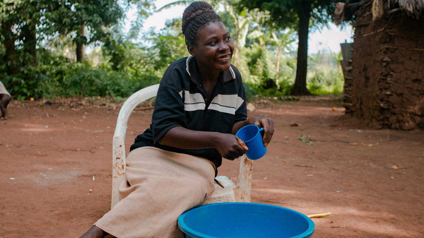 A woman sits in a chair with a cup and bucket.