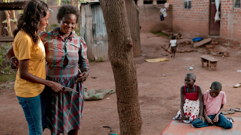 Sightsavers staff member Doreen speaks to a woman while her children sit on the floor.