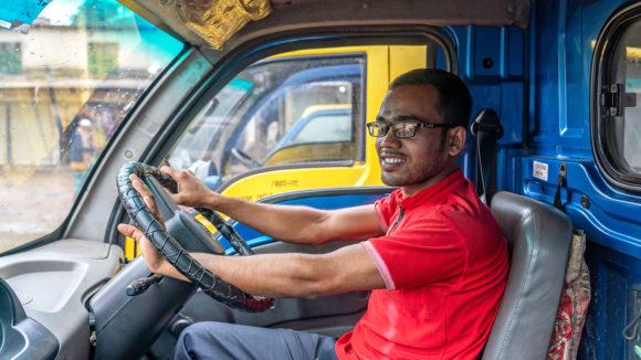 A young man sitting in the driver seat of a van.