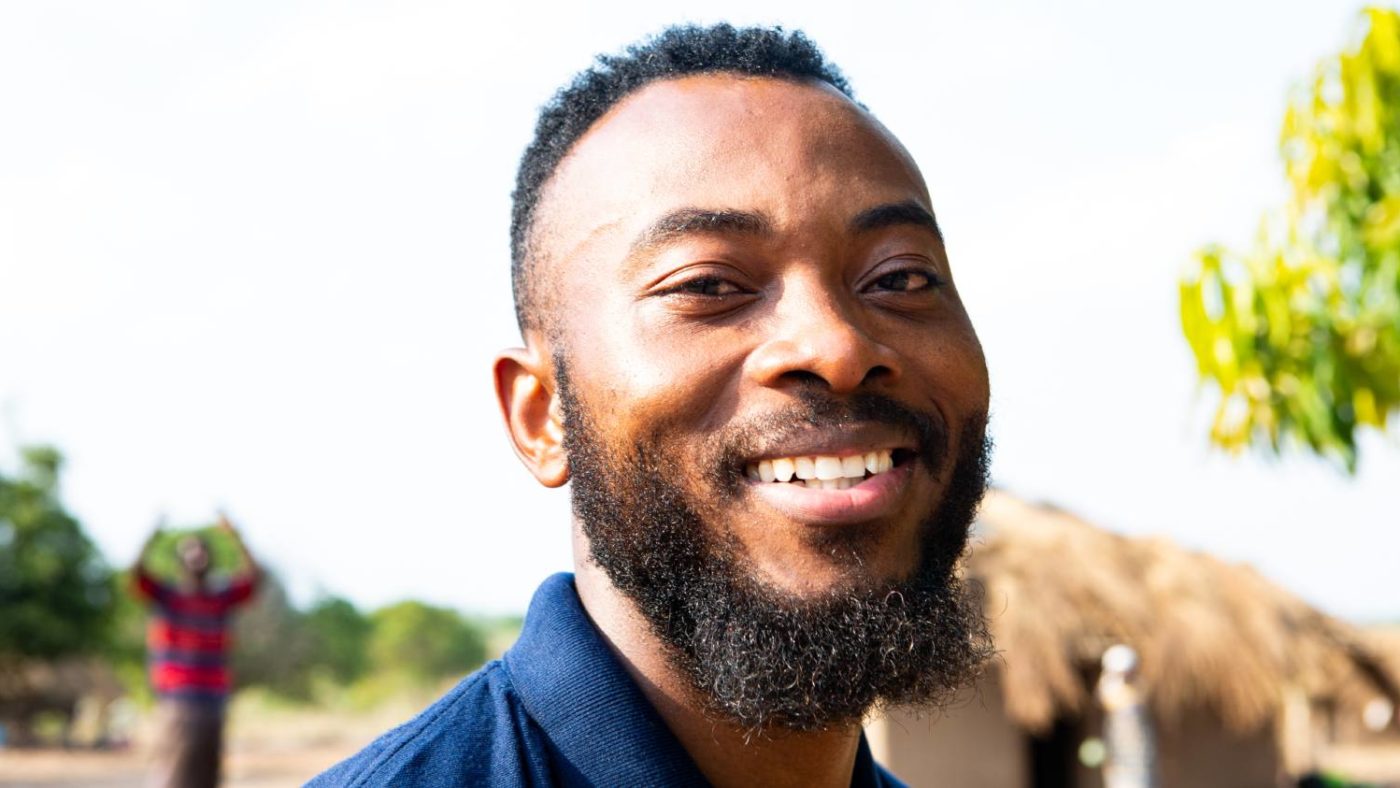 A man stands for a portrait outside after completing surveys for river blindness in Mozambique.